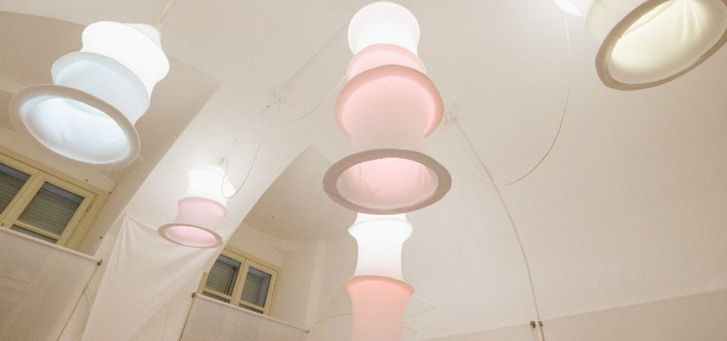 Grossi lampadari bianchi fatti a tubo pendono dal soffitto