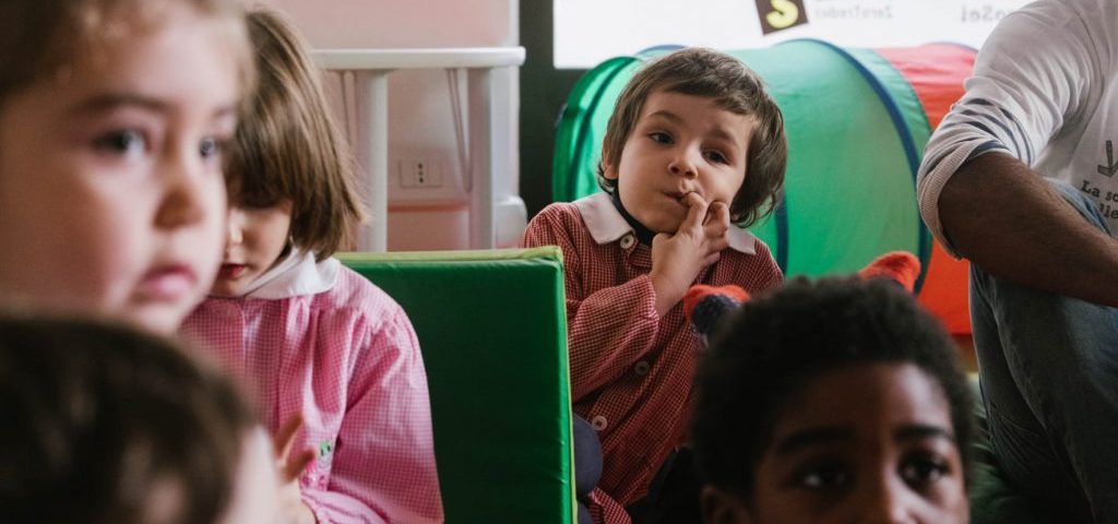 Alcuni bambini guardano nella stessa direzione, forse ad scoltare un'insegnante che parla