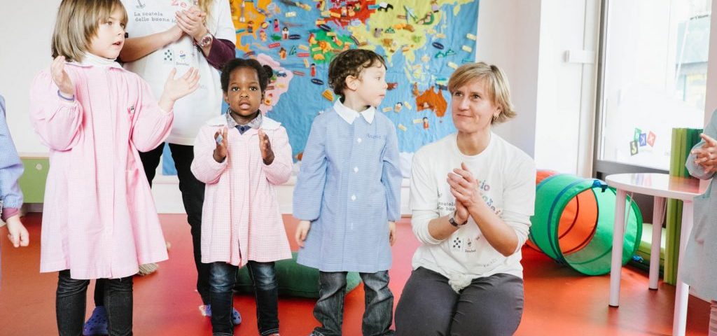 Un gruppo di bambini con due insegnanti muove le mani per formare ombre