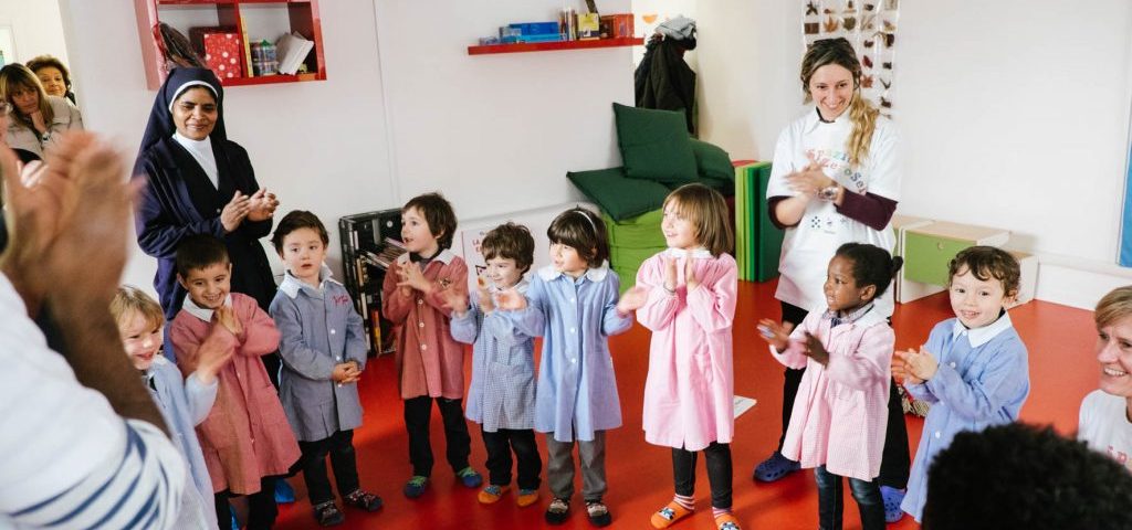 Un gruppo di bambini con una suora e un'insegnante che muovono le mani per formare ombre