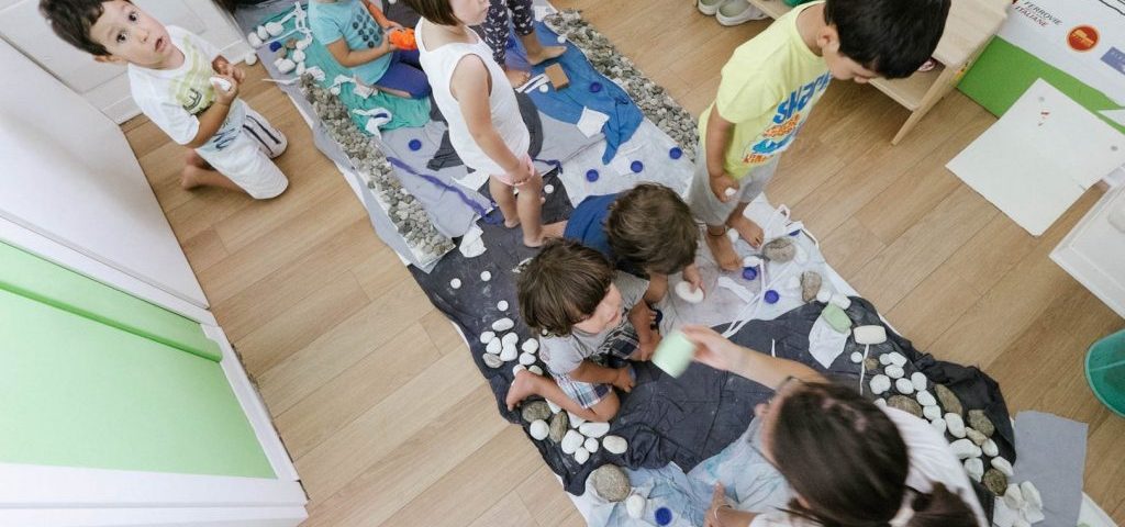 Bambini a piedi nudi seguono un percorso con sassi e materiali diversi