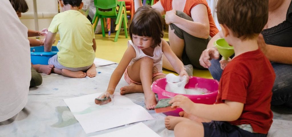 Bambini giocano con acqua e sapone e con l'acqua colorata dipingono fogli